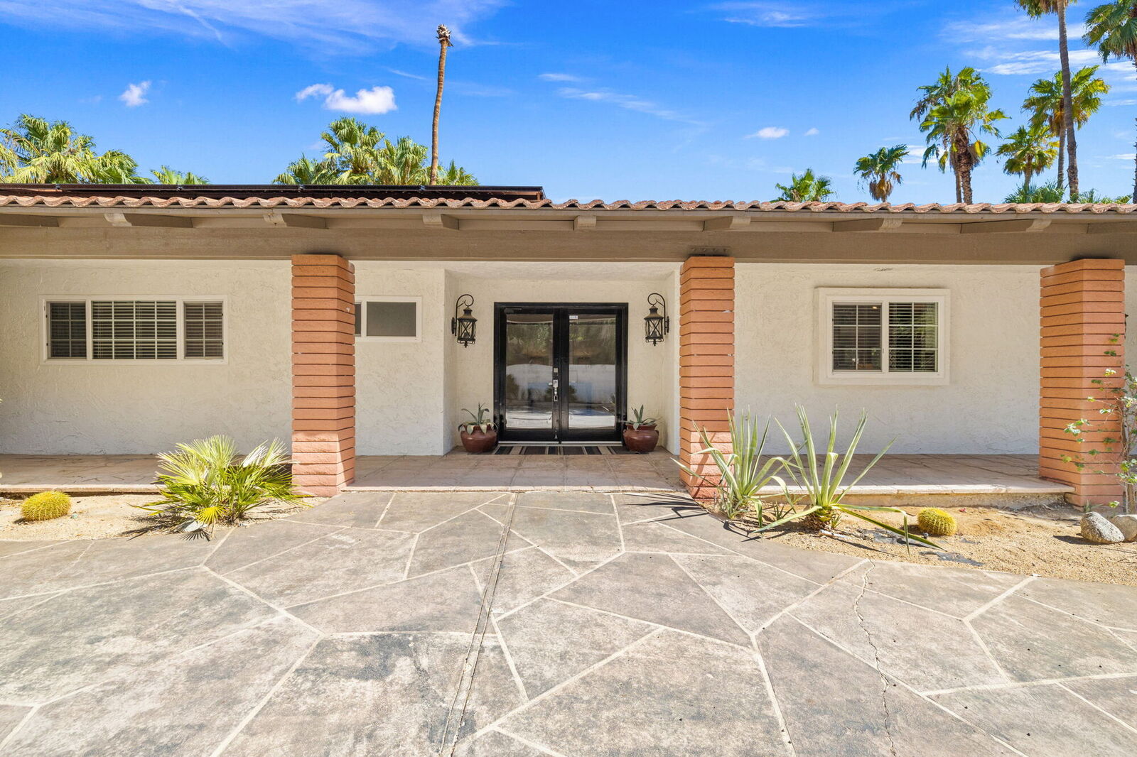 Front exterior of Villa 700 with desert landscaping and palms against a blue sky
