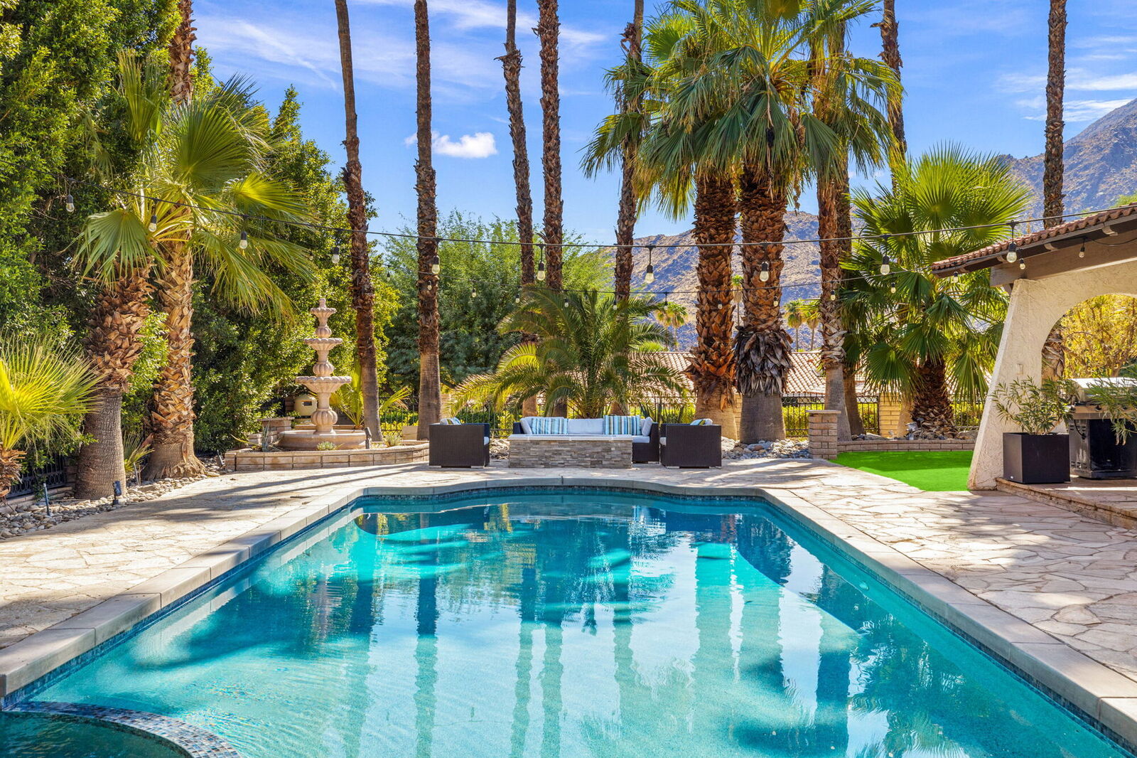 Villa 700 pool with clear blue water, ringed by palms with a mountain backdrop