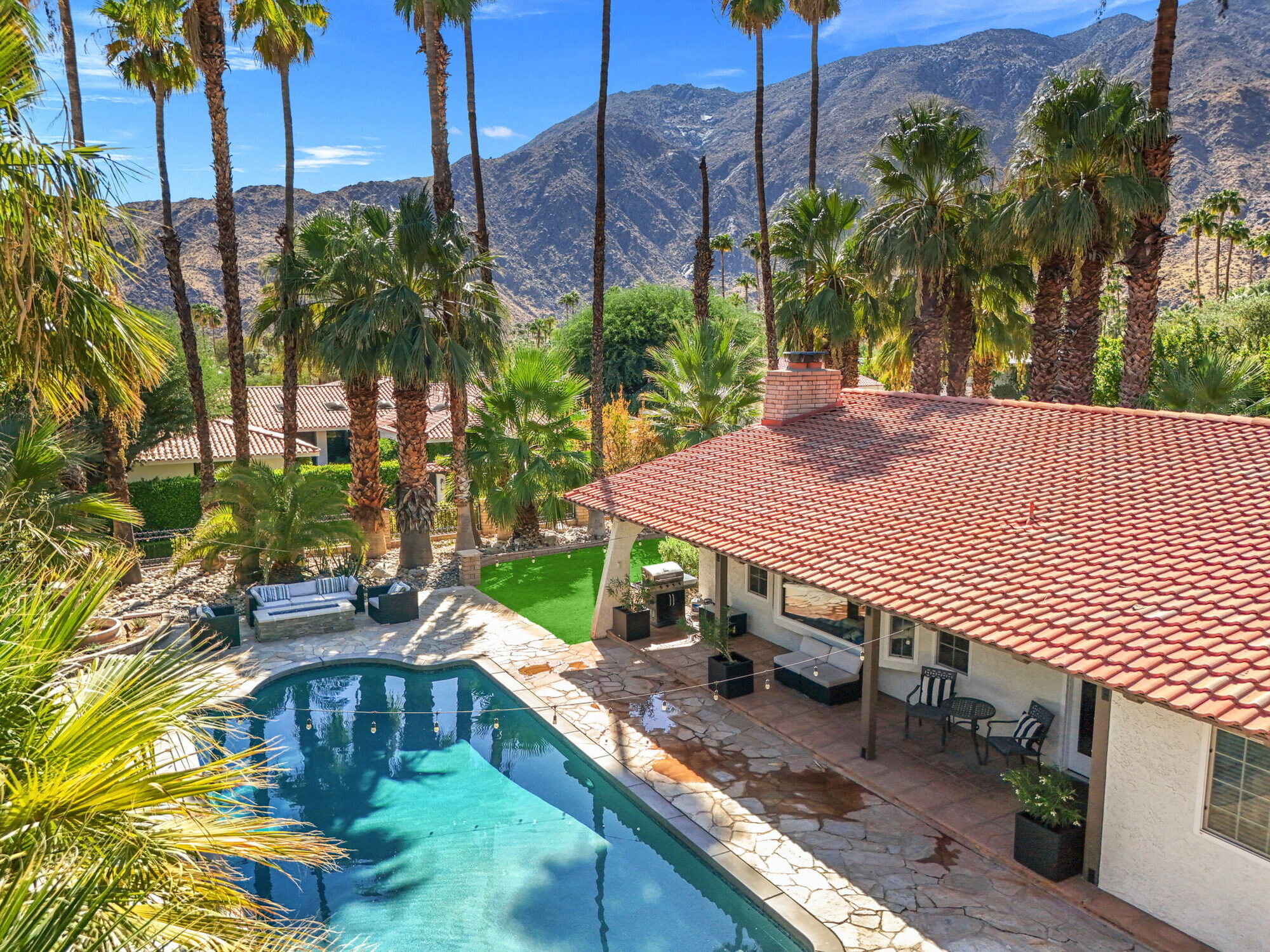 Aerial view of Villa 700 with its pool, red-tile roof, and palms framed by the San Jacinto mountains
